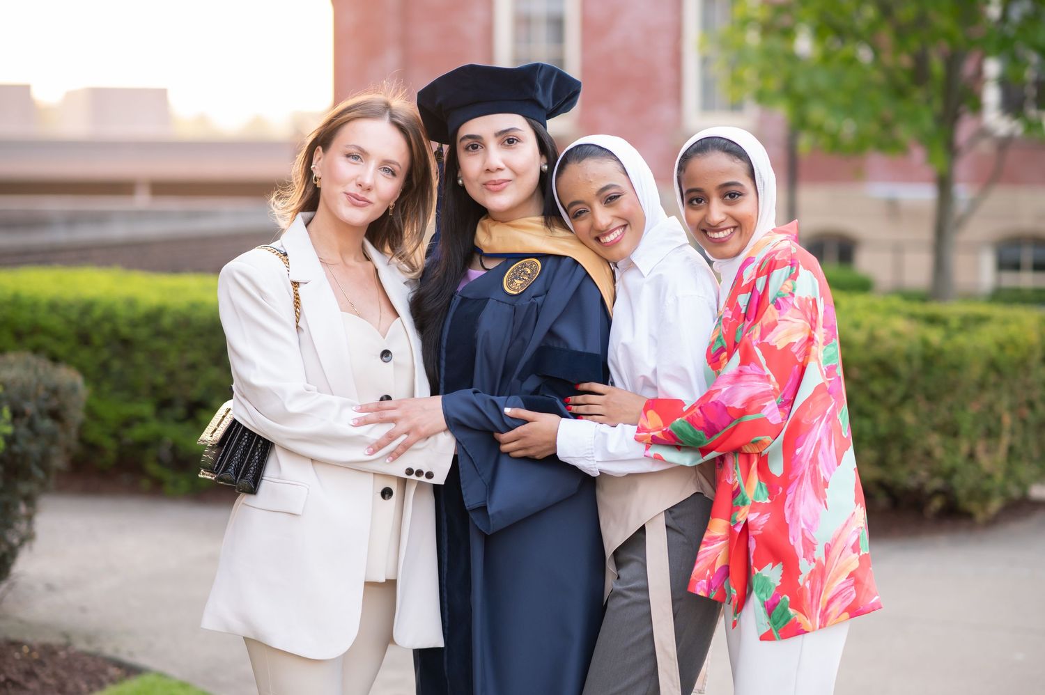 four young women pose together for a portrait with their graduating friend in front of Woodburn Hall in Morgantown, WV