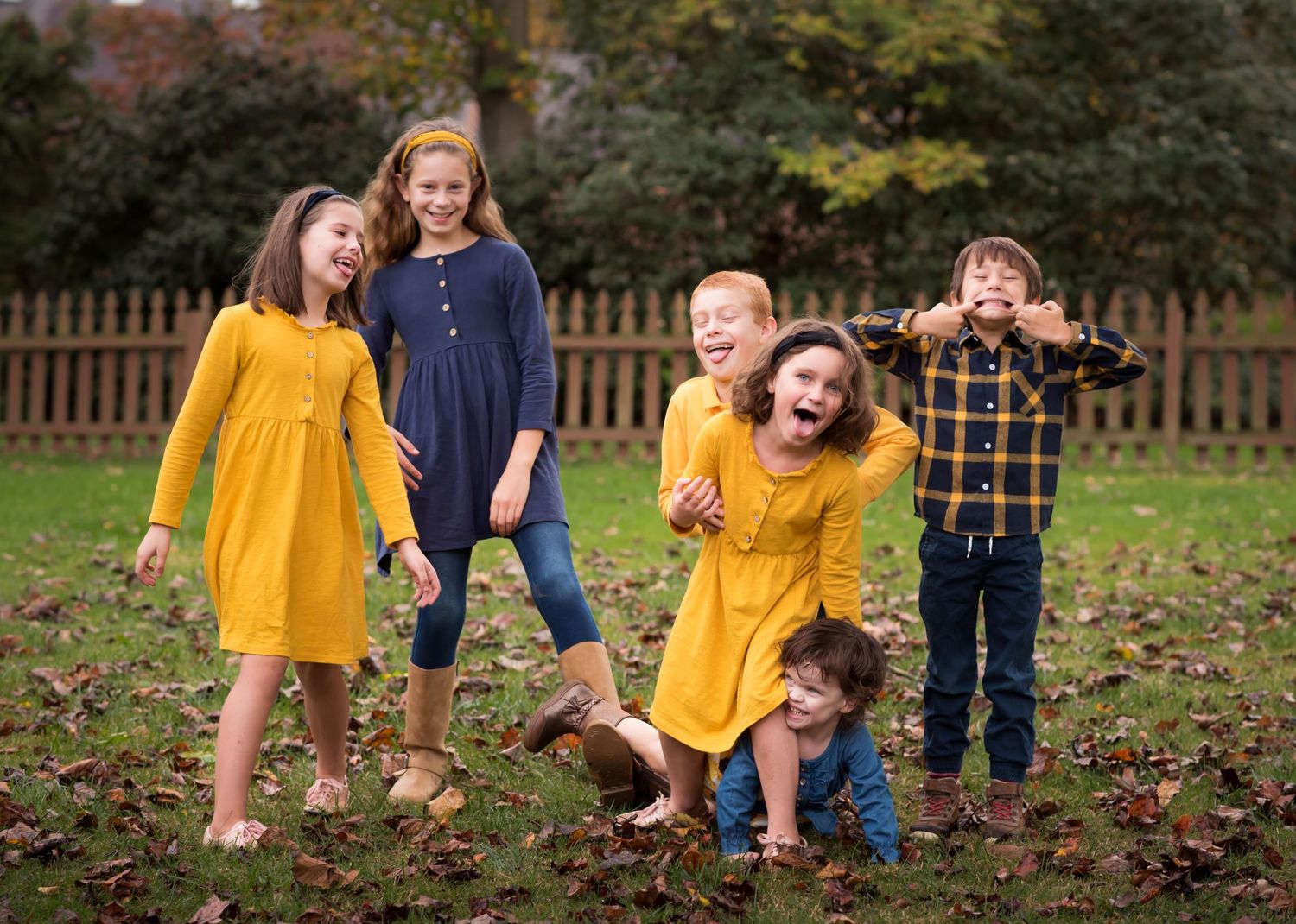 candid portrait of five young siblings dressed in gold and blue laughing and goofing off in their backyard in Morgantown, WV