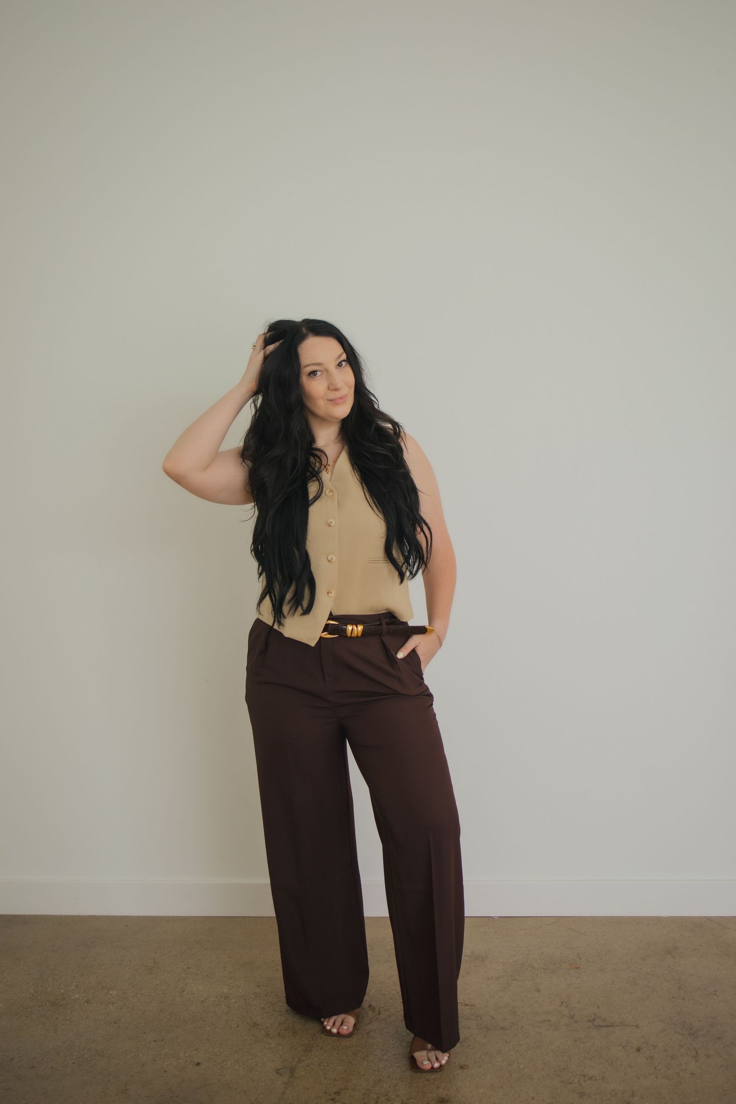 A person in a beige top and brown pants poses against a light wall showing different angles of their outfit.