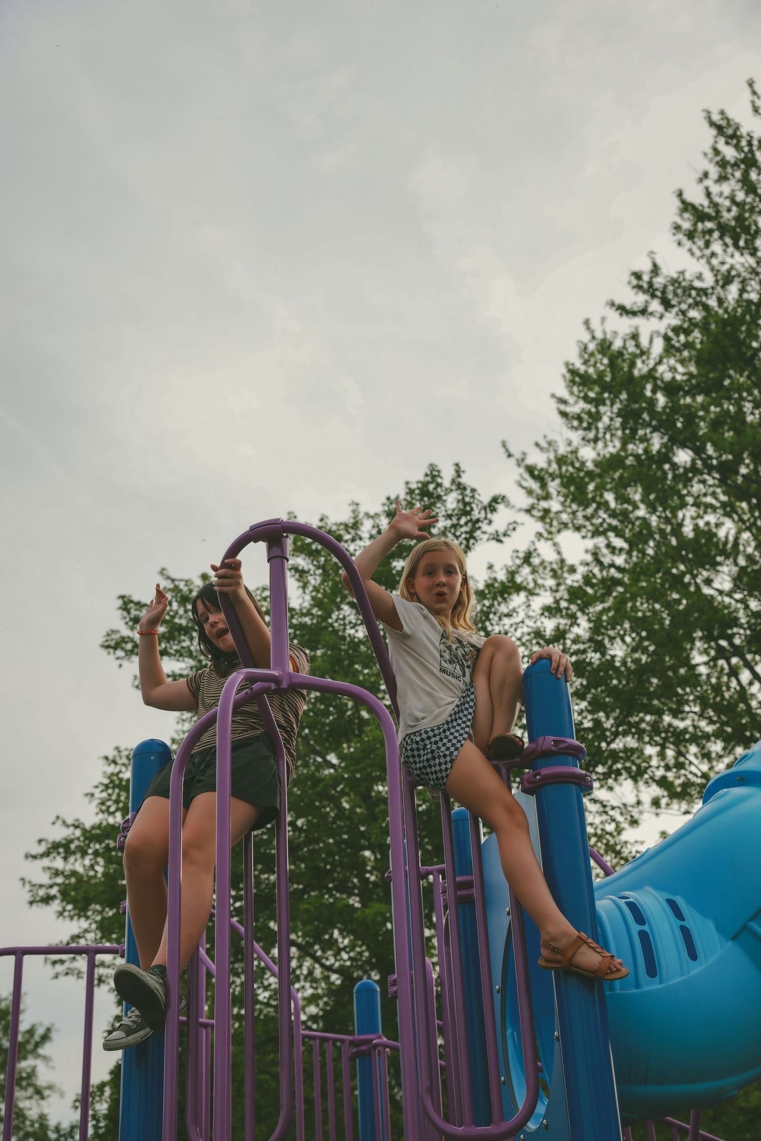 A sequence of action shots showing someone swinging and flipping on outdoor playground equipment on a cloudy day.