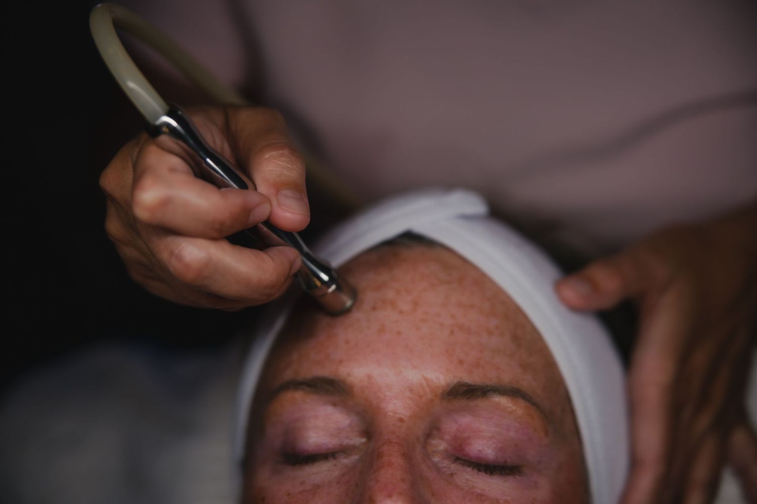 Person receiving permanent makeup procedure with cosmetic ink application to the eyebrow area.