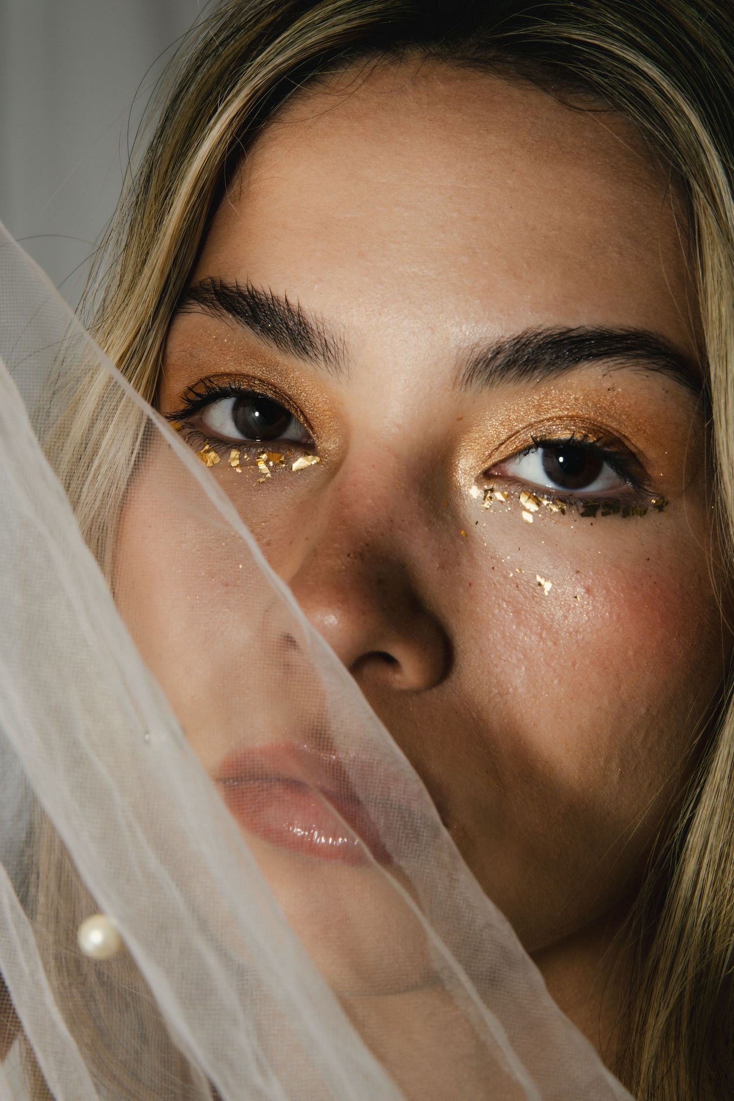 Close up beauty portrait with shimmering eye makeup and sheer veil showing modern bridal glamour shot.