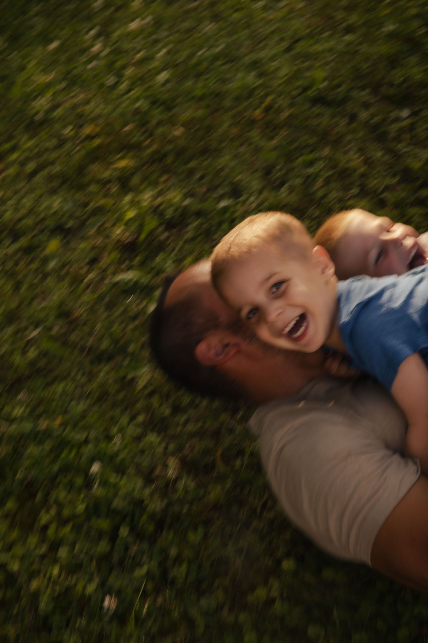 A joyful moment of play and laughter captured on grass in warm sunlight.