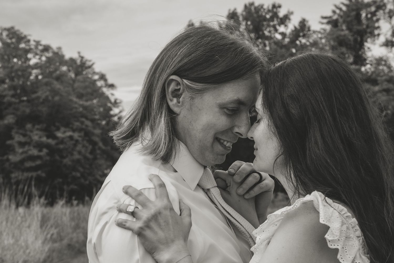A romantic black and white photo of a couple sharing an intimate moment together outdoors in a natural setting.