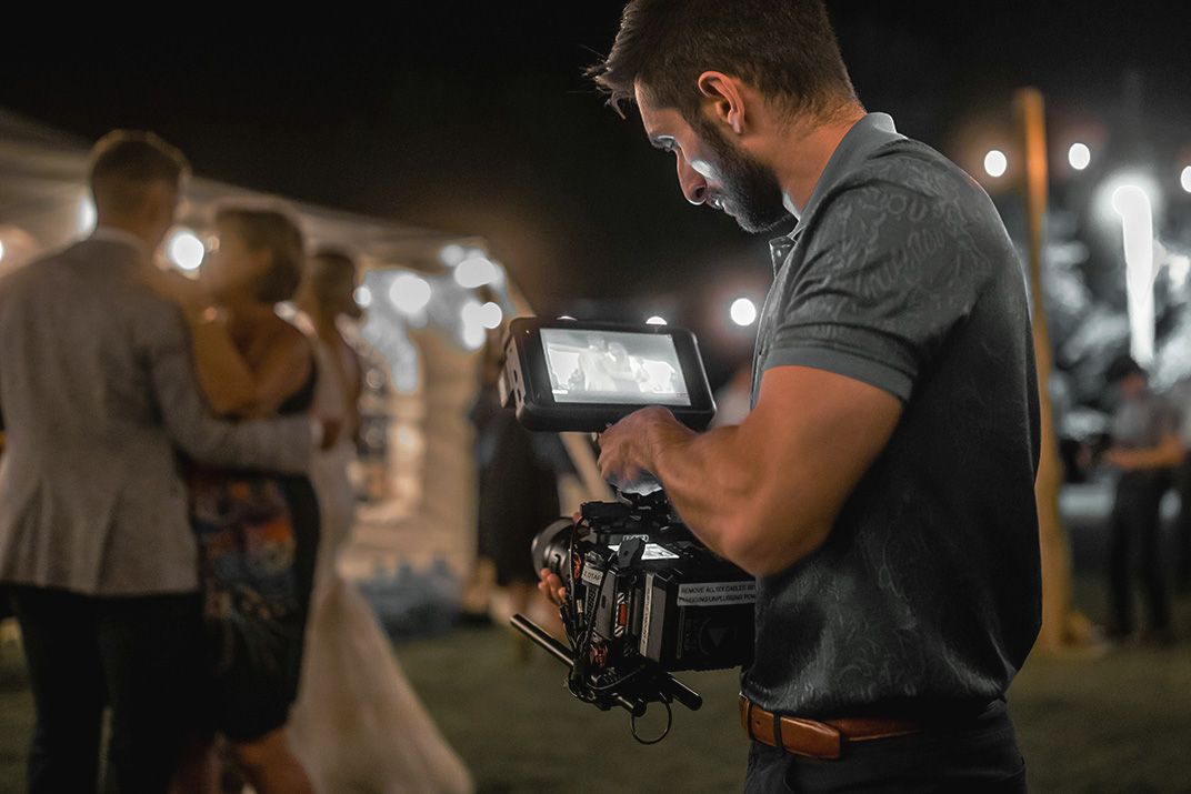 Videographer operates professional camera equipment while filming an outdoor nighttime event.