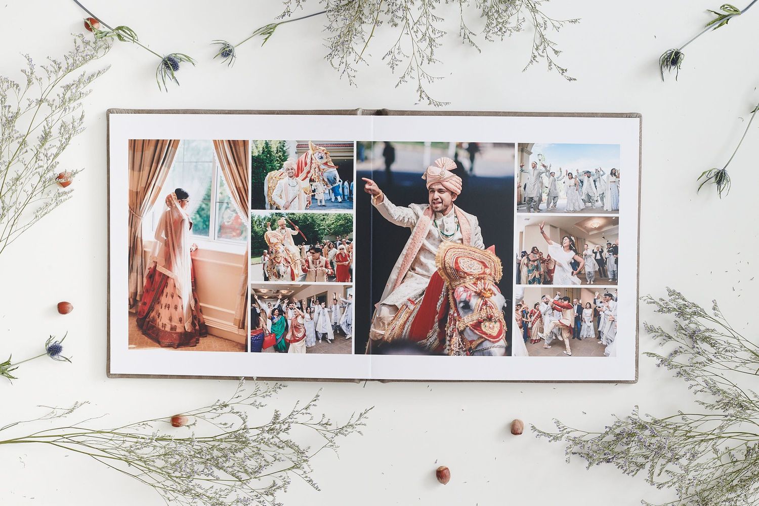 Elegant wedding photo album spread displayed on white surface with delicate greenery and red berry decorations.