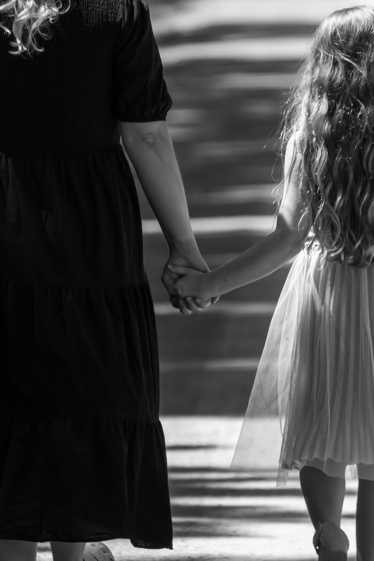 Black and white photo showing a tender moment between parent and child holding hands.