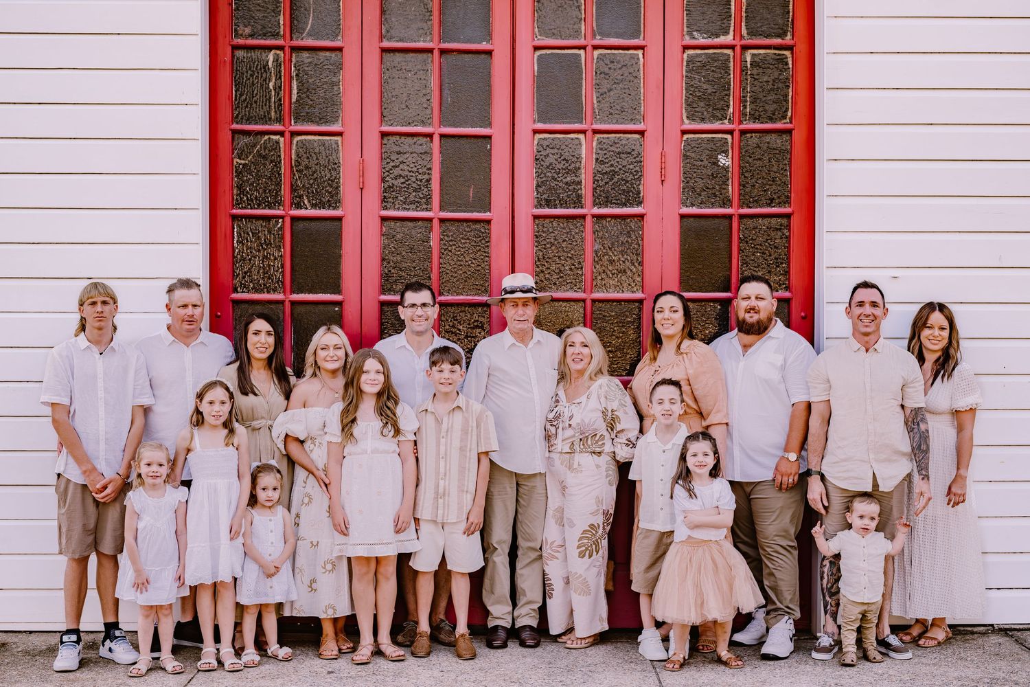 Large family portrait in front of a white church building with red trim.