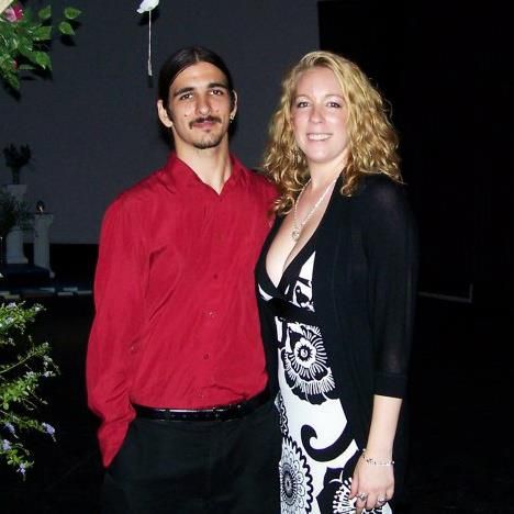 A couple poses together at an evening event, with a person in red and another in a black and white patterned dress.