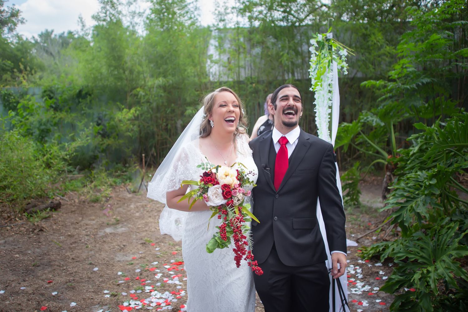 Joyfully celebrating couple walking outdoors in natural setting with wedding attire and bouquet. Tampa Photographer, Tampa Videographer