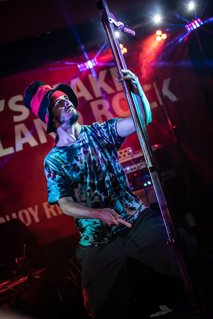Performer on stage grabs microphone stand emotionally under colorful red and purple concert lighting at rock show. Tampa Photographer