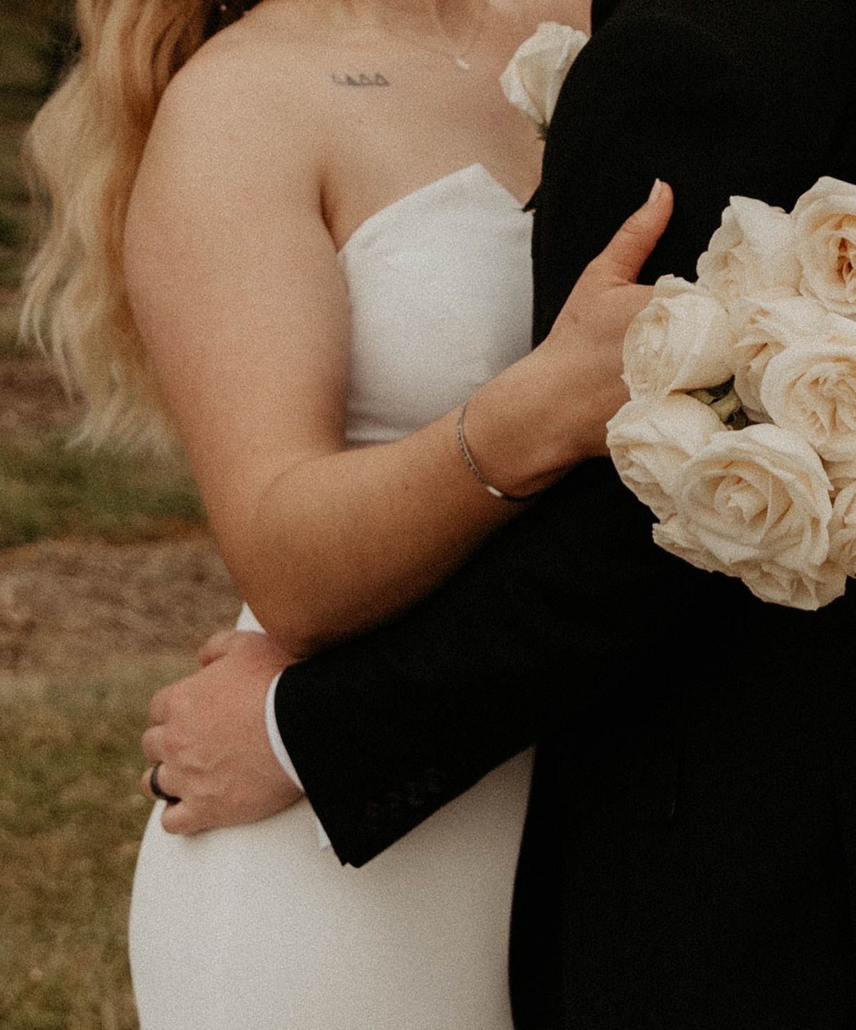 Close-up of bride and groom embracing, showcasing white bouquet and formal attire.