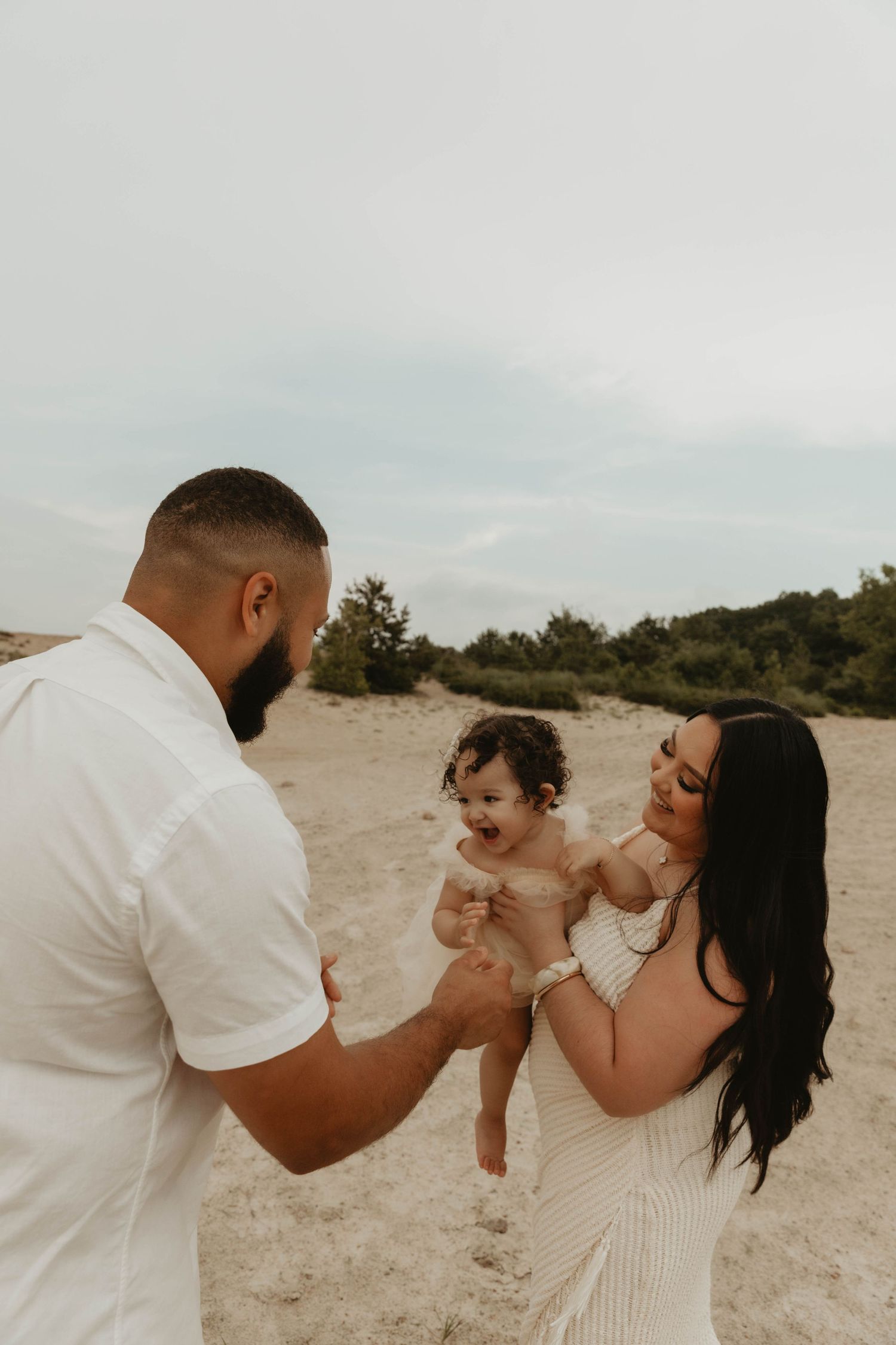 Candid family moment captured on sandy beach with natural lighting.
