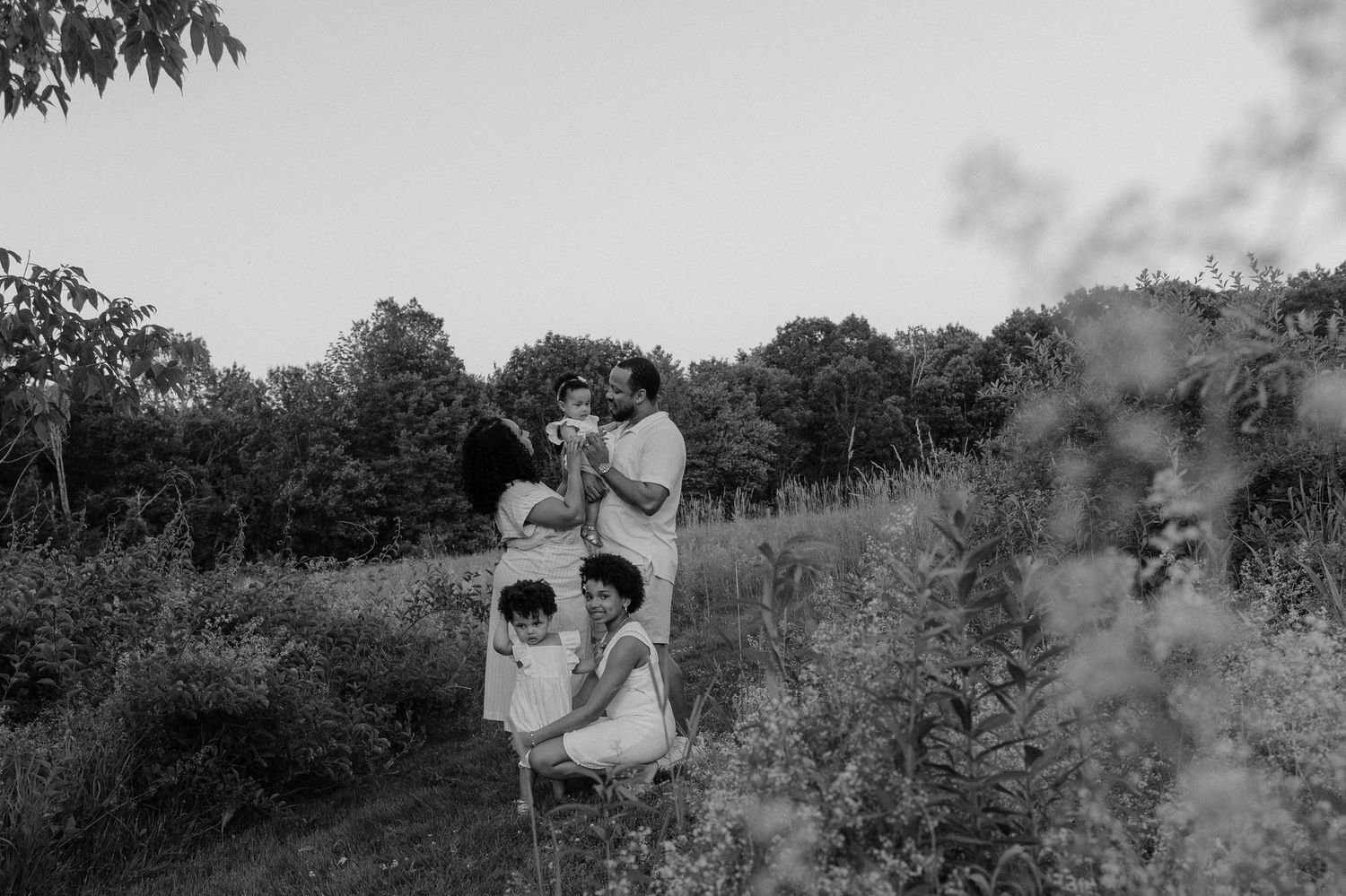 A black and white panoramic photograph showing people standing in an orchard setting during what appears to be harvest time.