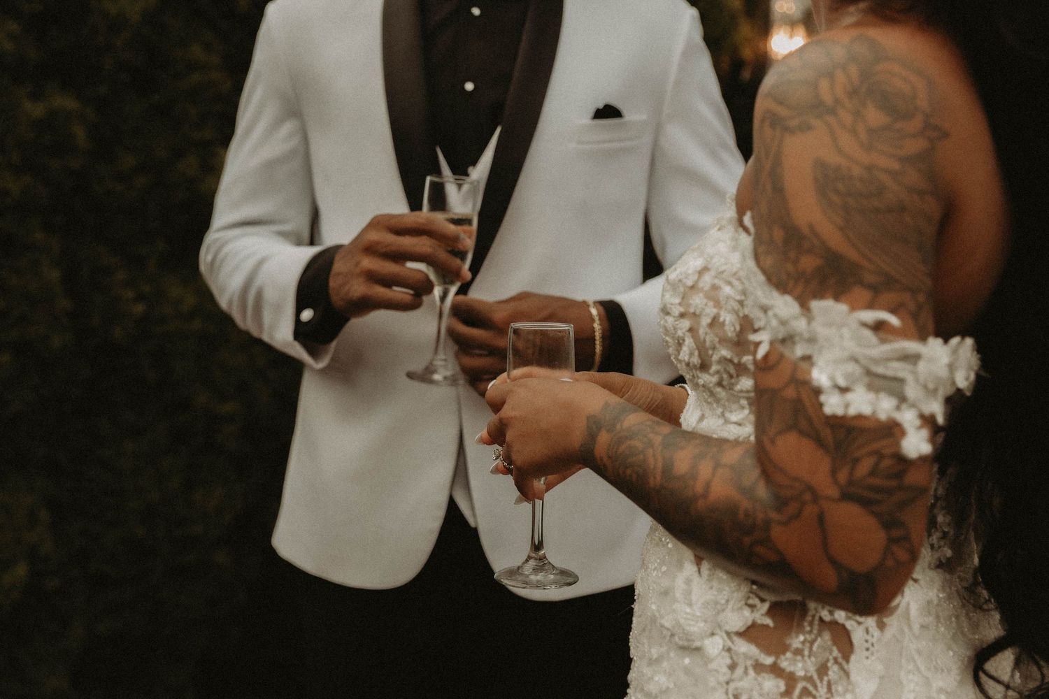 Wedding couple holding champagne glasses in elegant white and black attire.