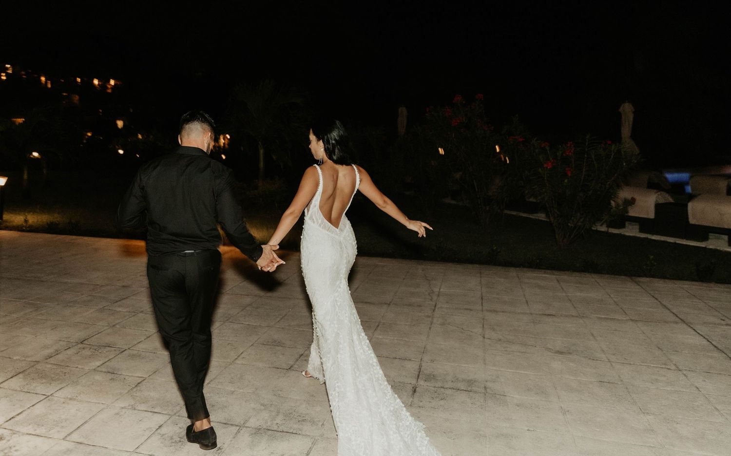 Couple dancing at night on outdoor reception floor with flowing white dress.