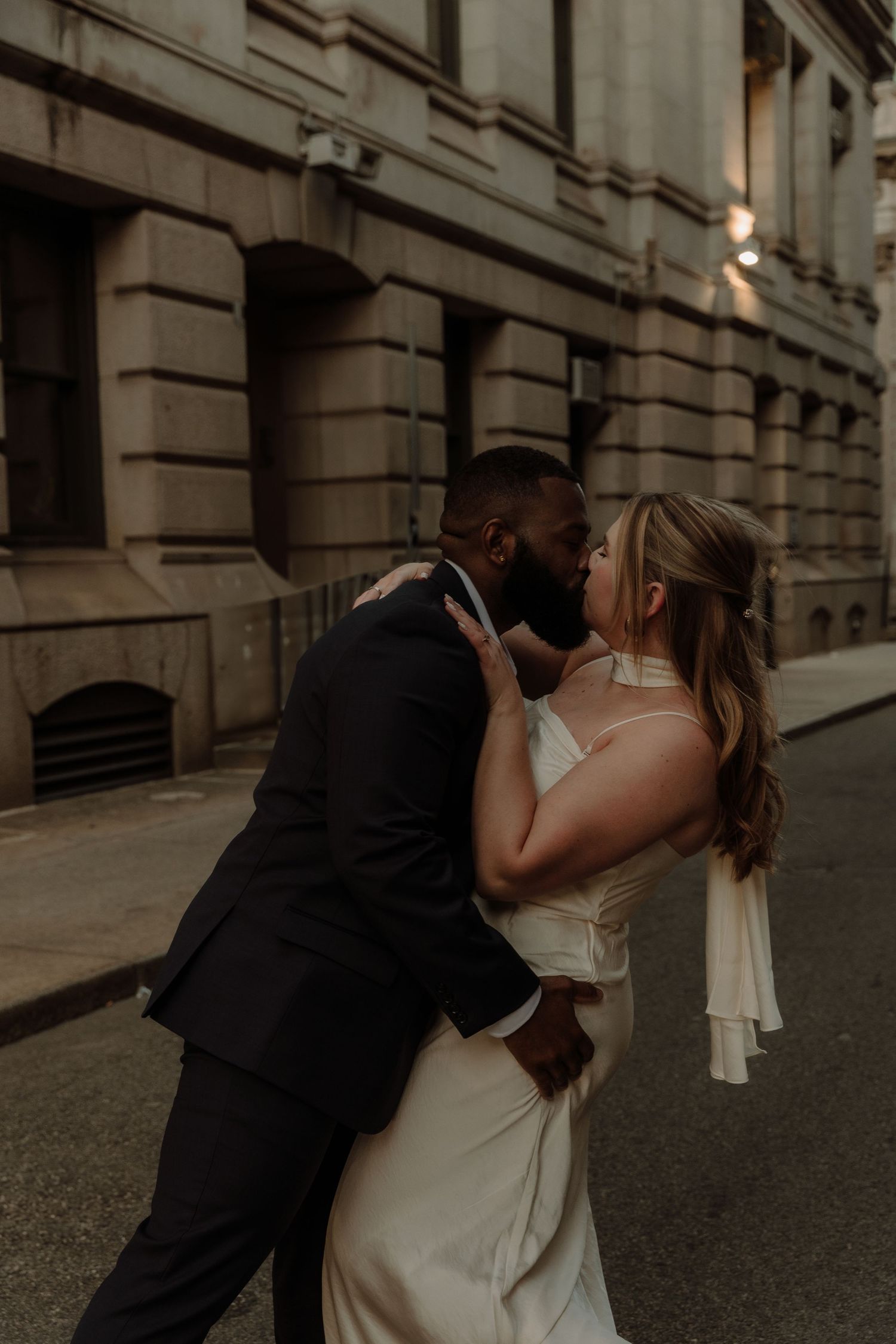 A romantic series of wedding photos showing a couple embracing and kissing in front of a historic stone building.