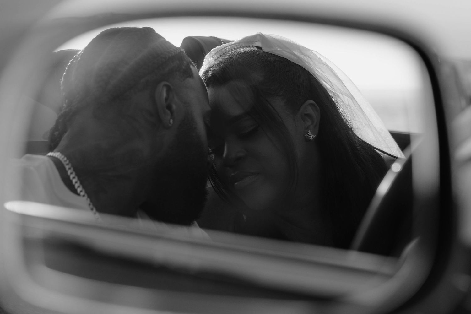 Intimate black and white reflection of a couple in a car mirror.