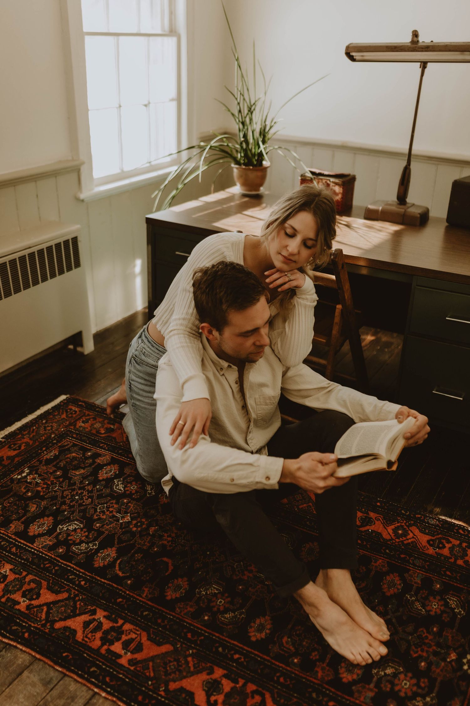 Couple relaxing together on patterned rug while reading.