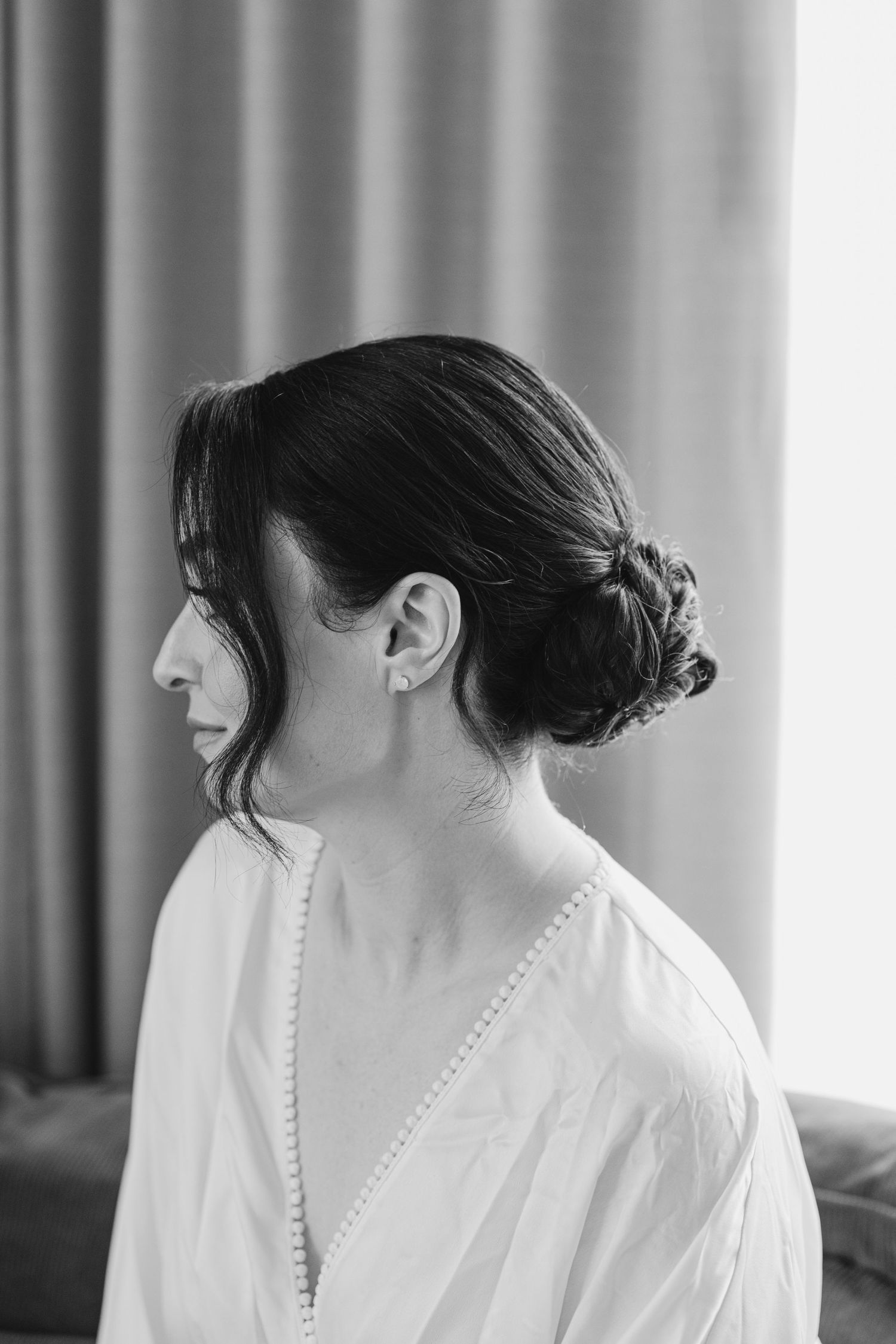 A black and white profile photo shows an elegant updo hairstyle with wispy bangs and a white v-neck top.