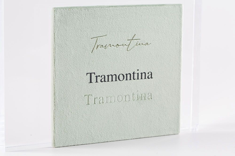 Several muted green and white business cards for Tramontina brand shown at different angles and distances.