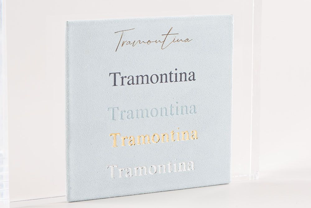 Close-up view of Tramontina logo text against white wall with multiple reflective surfaces.