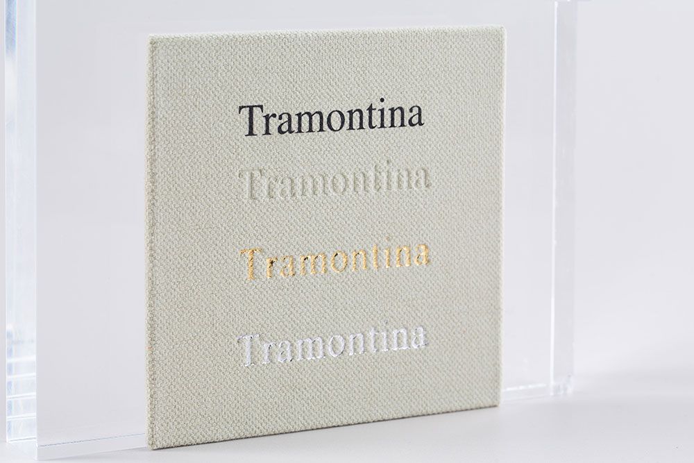 Close-up view of minimalist Tramontina text printed on a beige textured background.