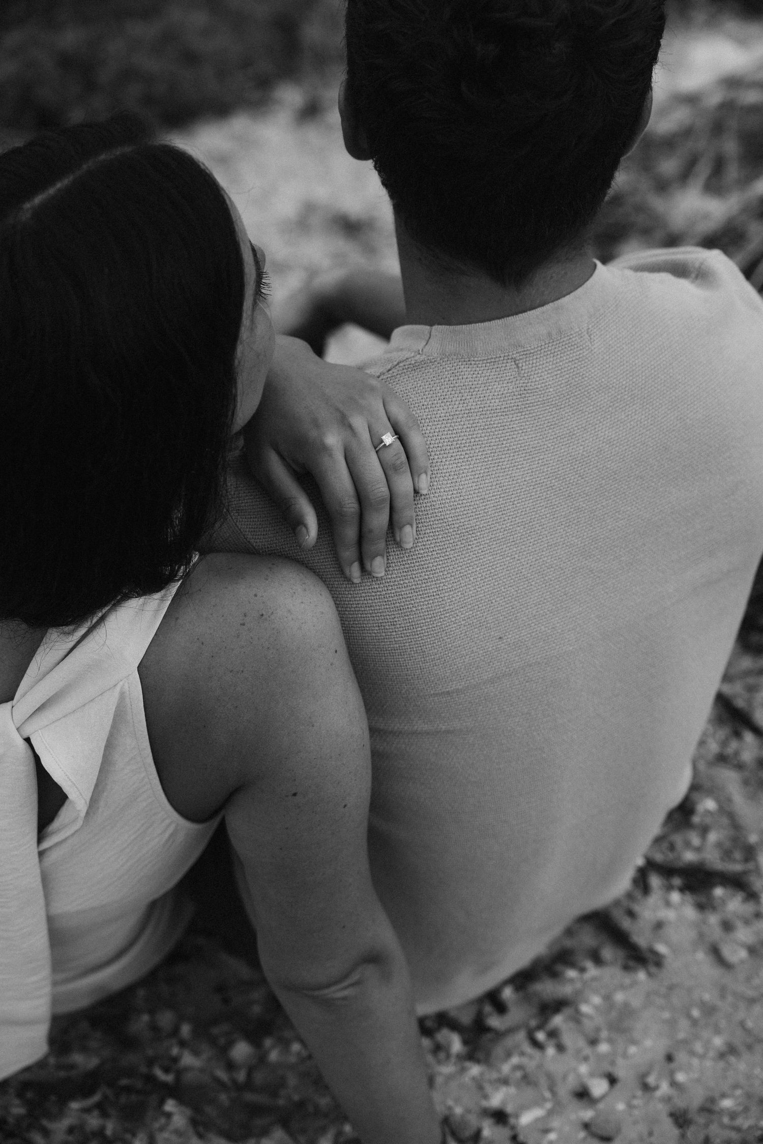 Black and white photo showing a couple sitting close together in a tender embrace.