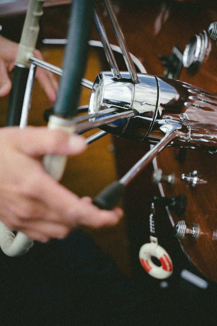 Metal tuning pegs on the headstock of an acoustic guitar shown in detail against a dark wooden background.