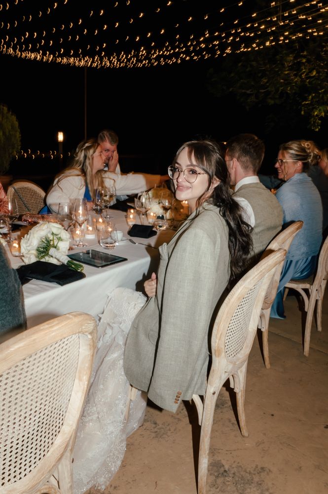 Evening wedding reception under string lights with guests seated at an elegant table setting.
