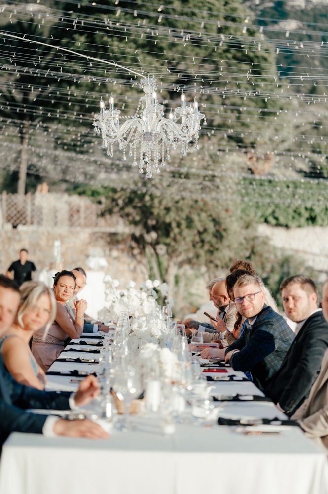 An elegant outdoor wedding reception with crystal chandeliers and string lights.
