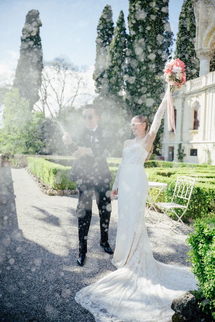 Couple stands in an ethereal garden setting with mist creating a romantic atmosphere as a bride's white dress flows beautifully.