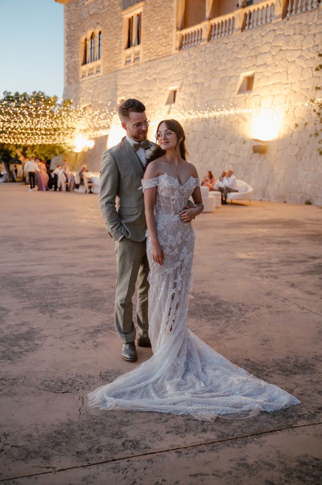 A romantic sunset wedding portrait against a stone castle backdrop.