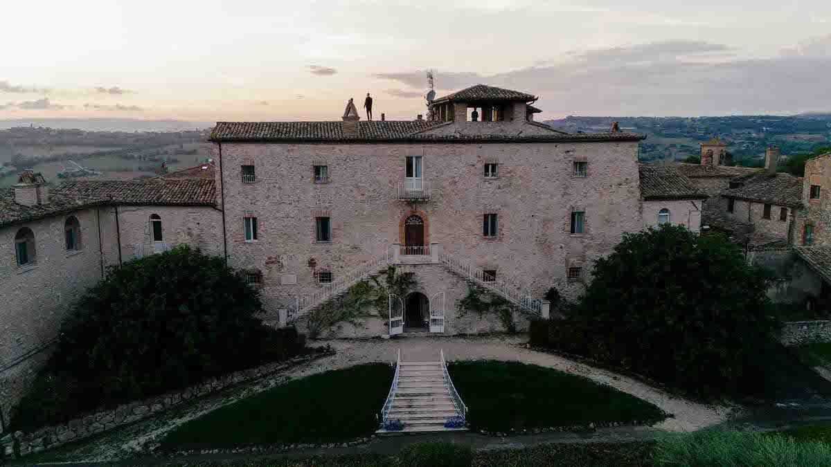 Historic Italian villa with symmetrical garden path and stone facade at dusk.