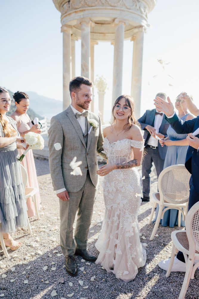 Wedding celebration under ornate stone gazebo with guests enjoying festive atmosphere.