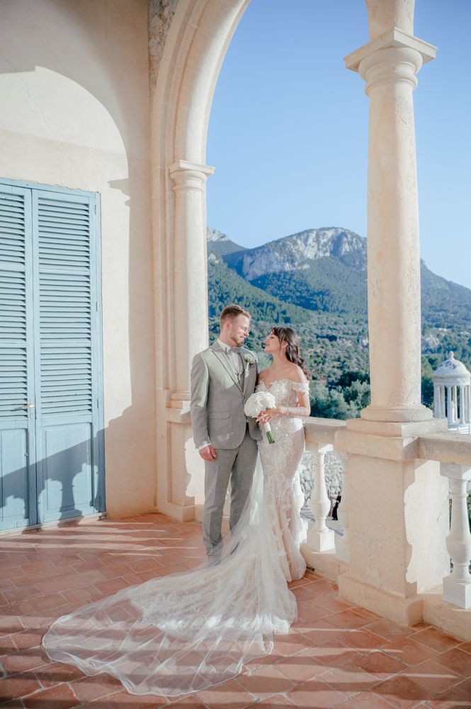 Wedding portrait on elegant terrace with arched columns and mountain views.