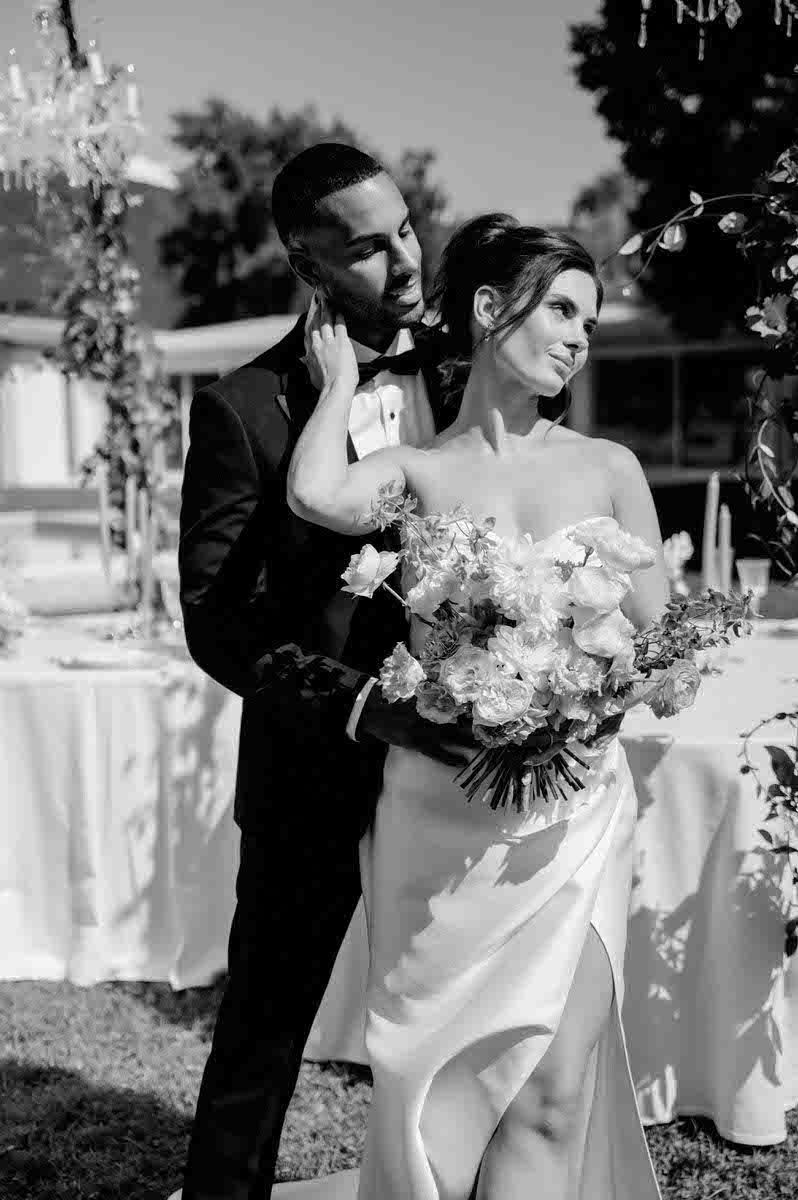 Romantic black and white portrait of couple with bridal bouquet in garden setting.