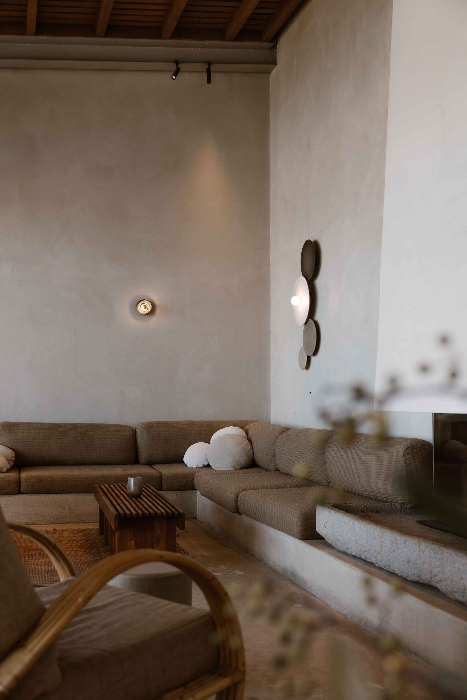 Minimalist living room with brown sectional sofa, curved wooden furniture, and wall-mounted lighting.