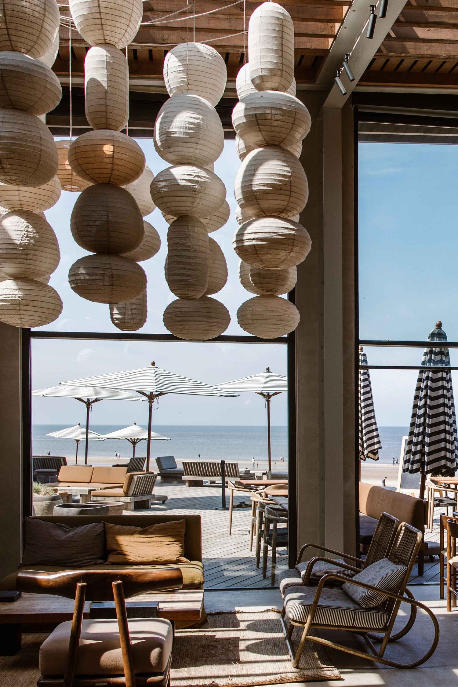 Beachside lounge area with hanging paper lanterns and outdoor umbrellas overlooking the ocean.