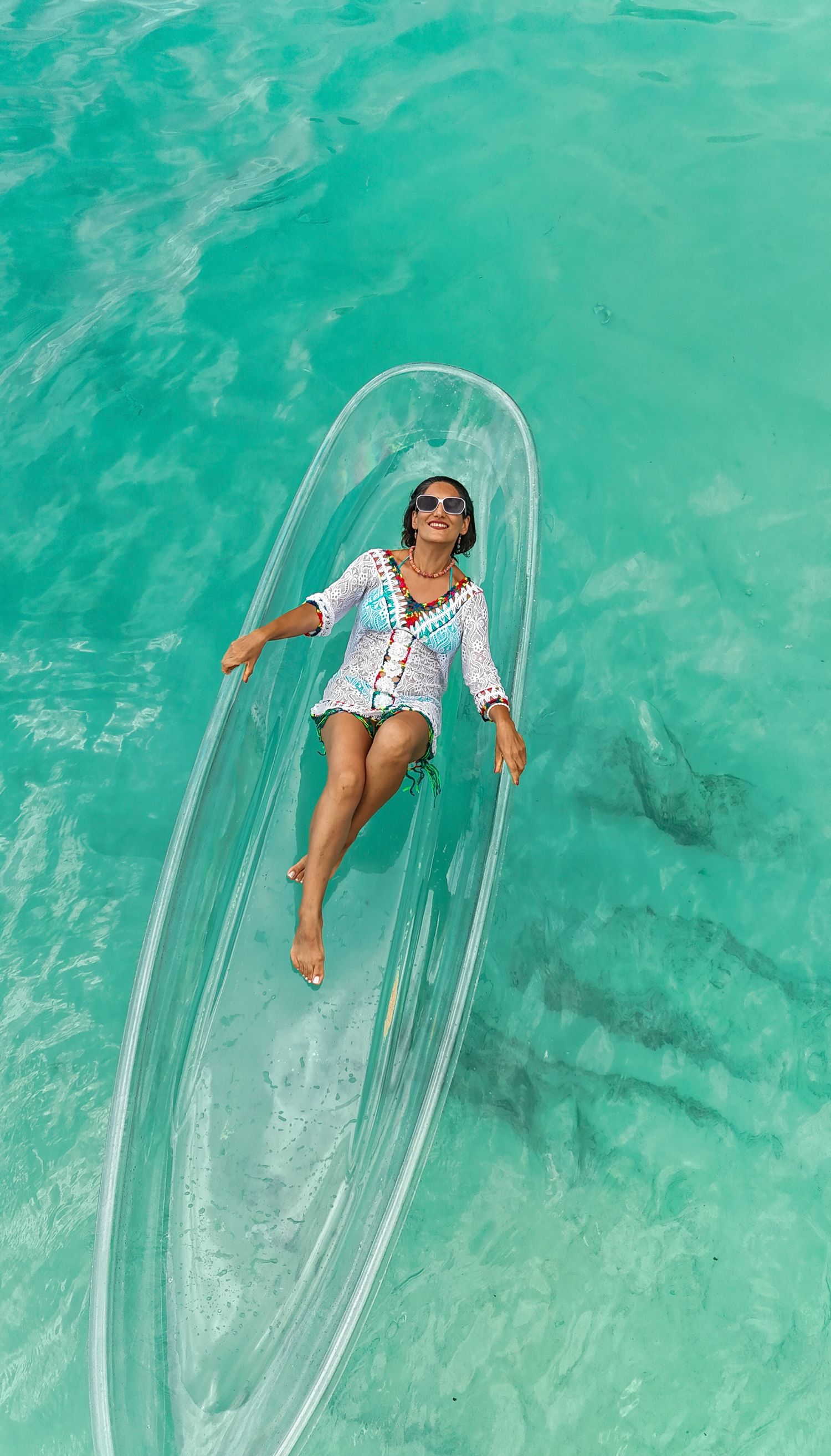 Aerial view of a clear kayak floating on turquoise tropical waters with beautiful model in the Seychelles.