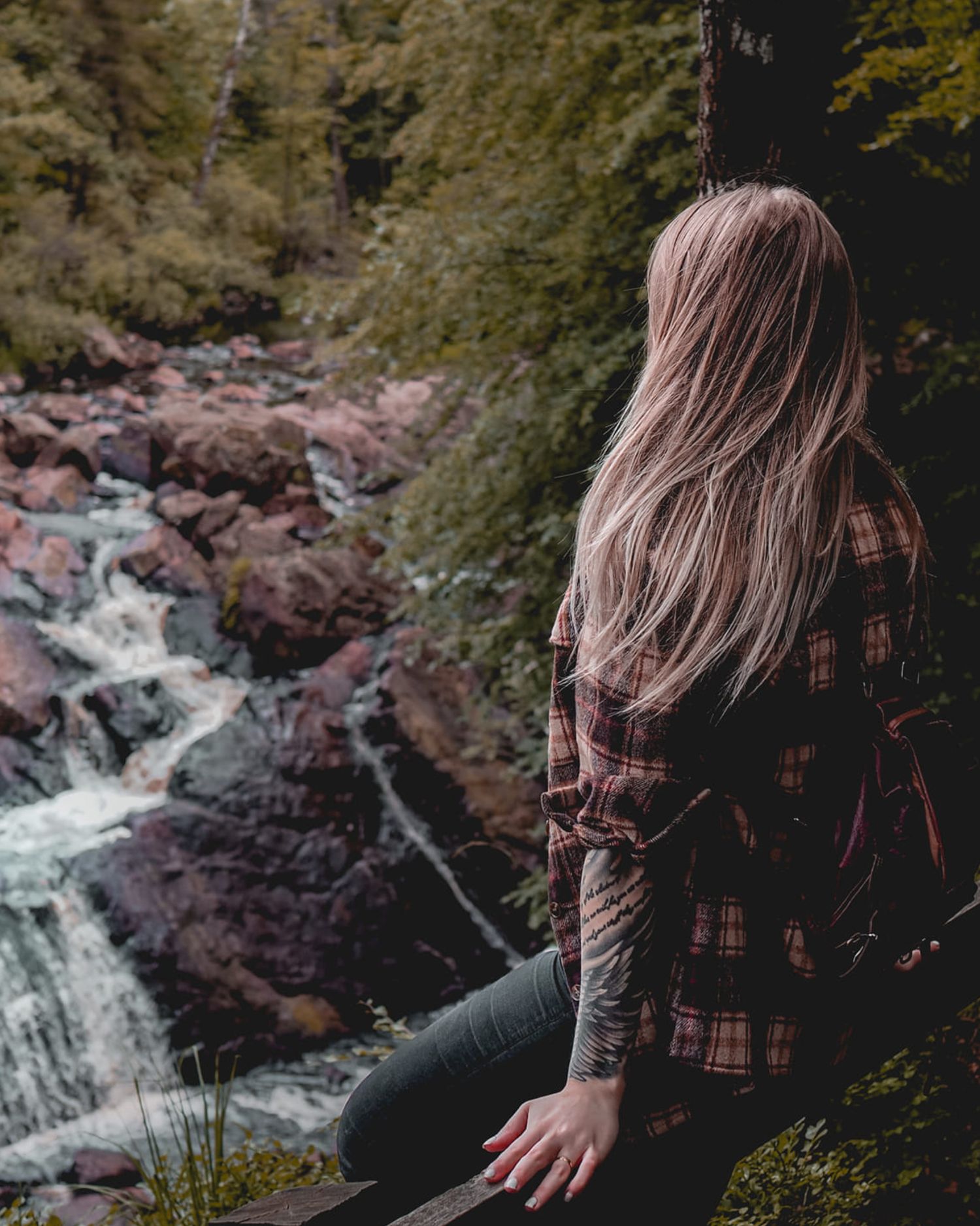 Kvinna sitter på klippa vid Danska Fall i Simlångsdalen och tittar mot vattenfallet.