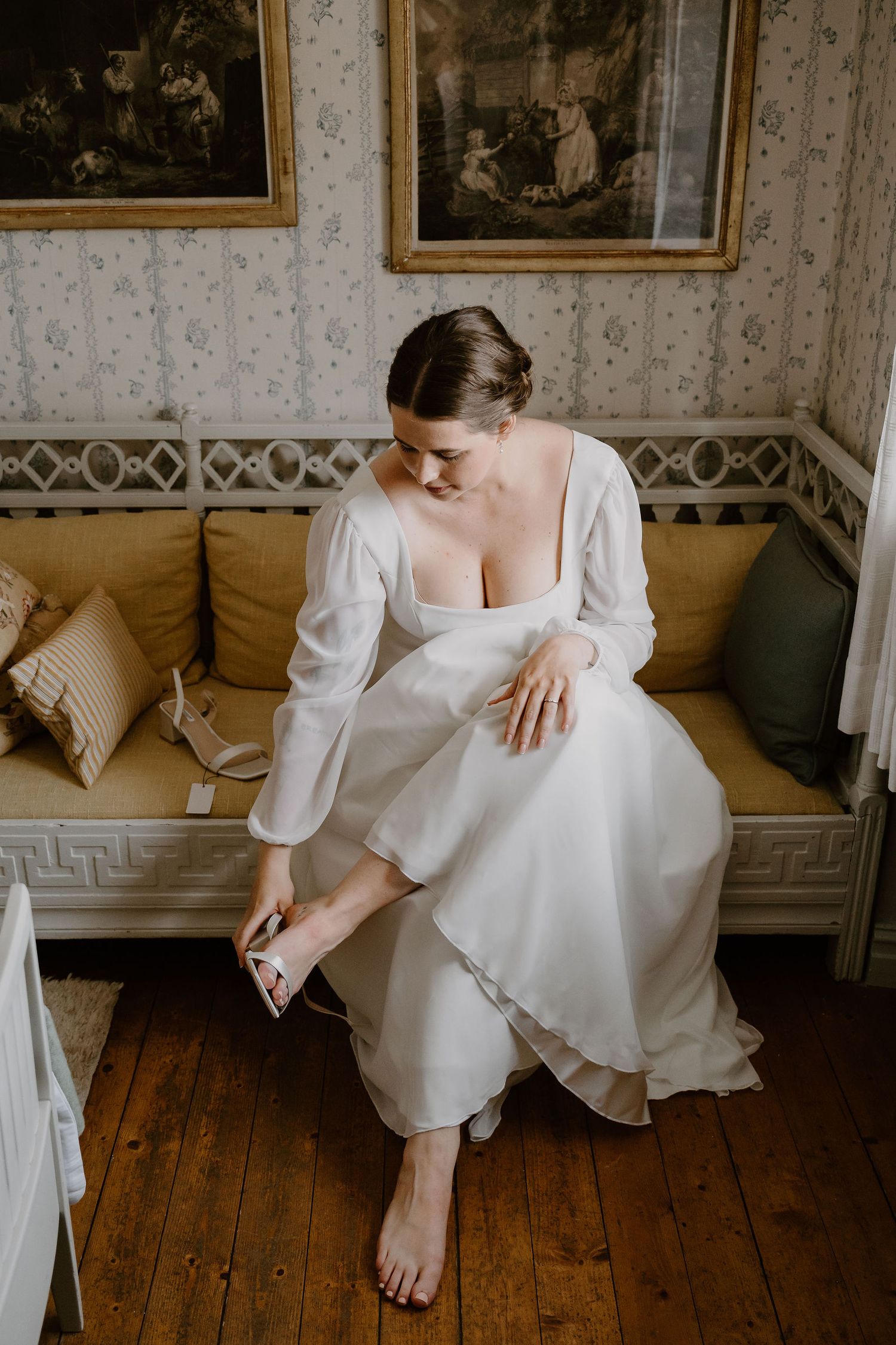 A figure in a white wedding dress sits elegantly on a vintage wooden floor in a classically decorated room.