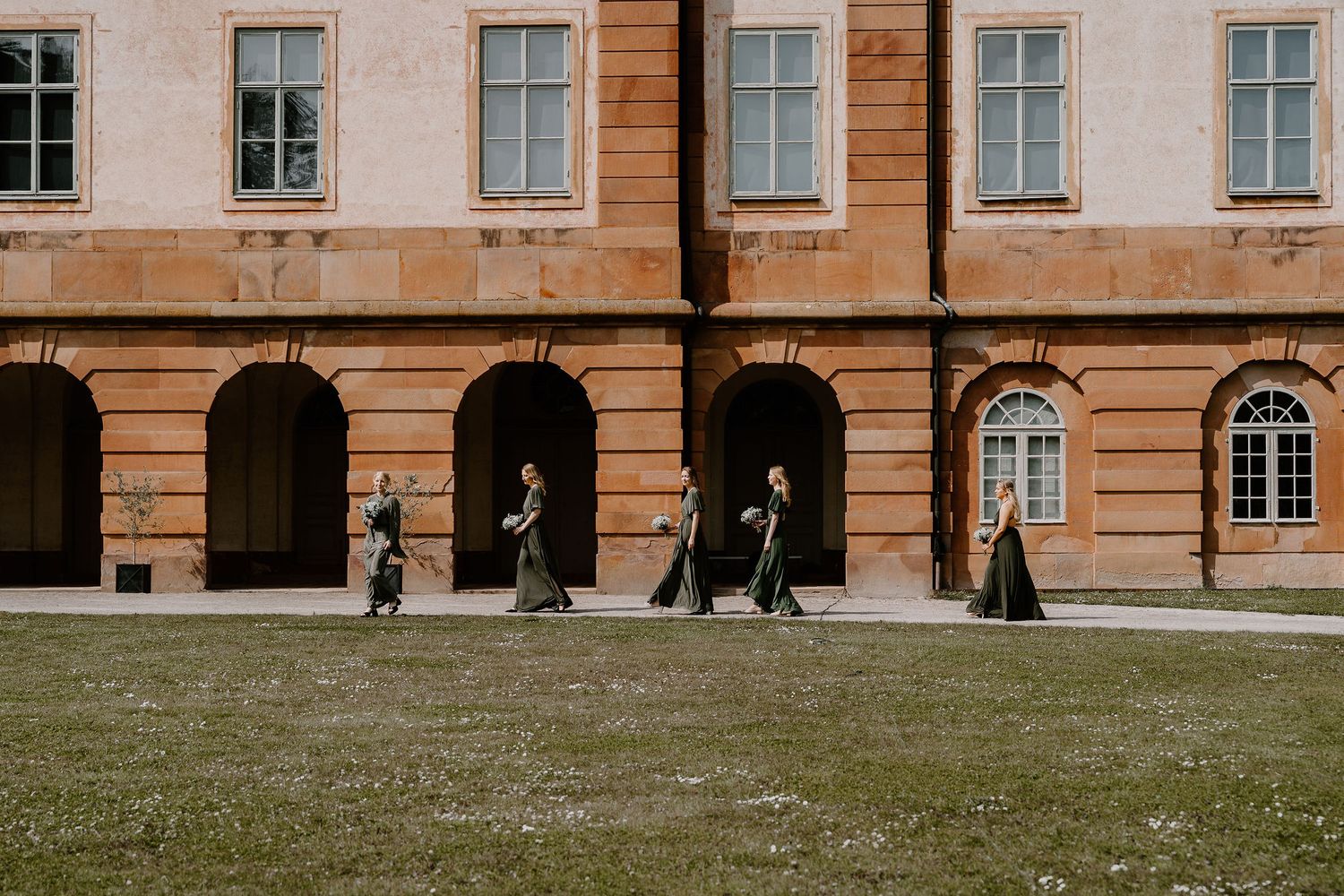 A series of arched windows line the facade of a historic orange-colored building with classic European architecture.
