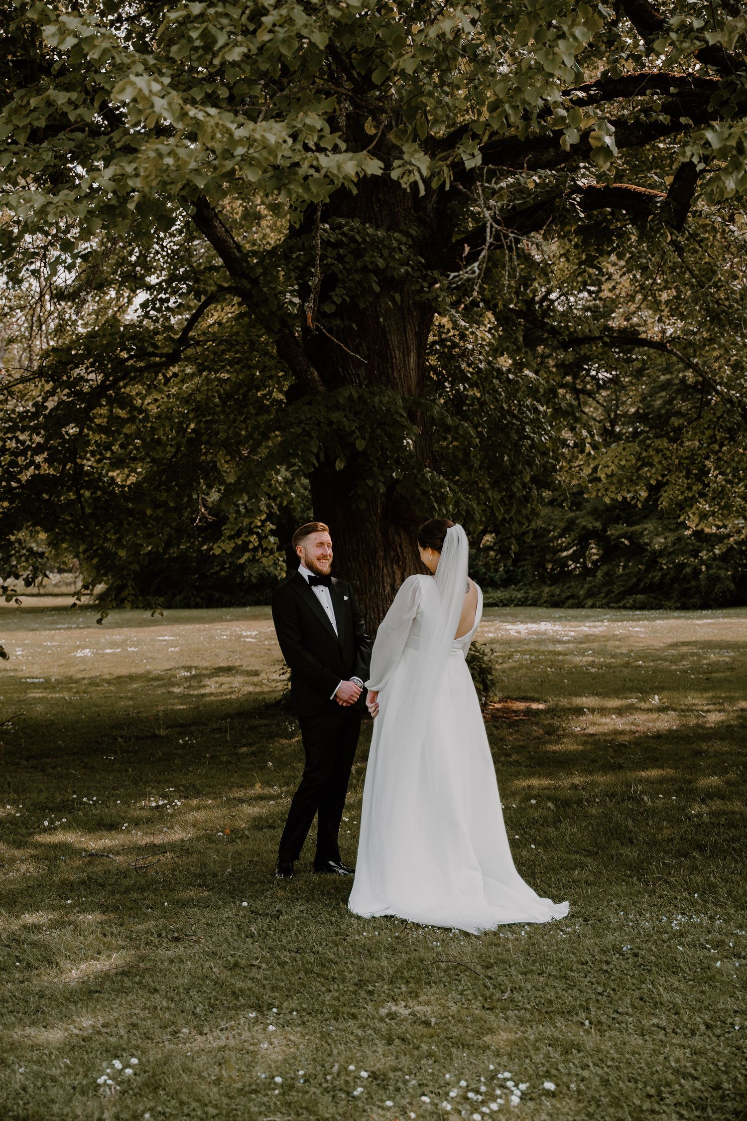 A wedding couple walks together through a serene garden setting on an autumn day.