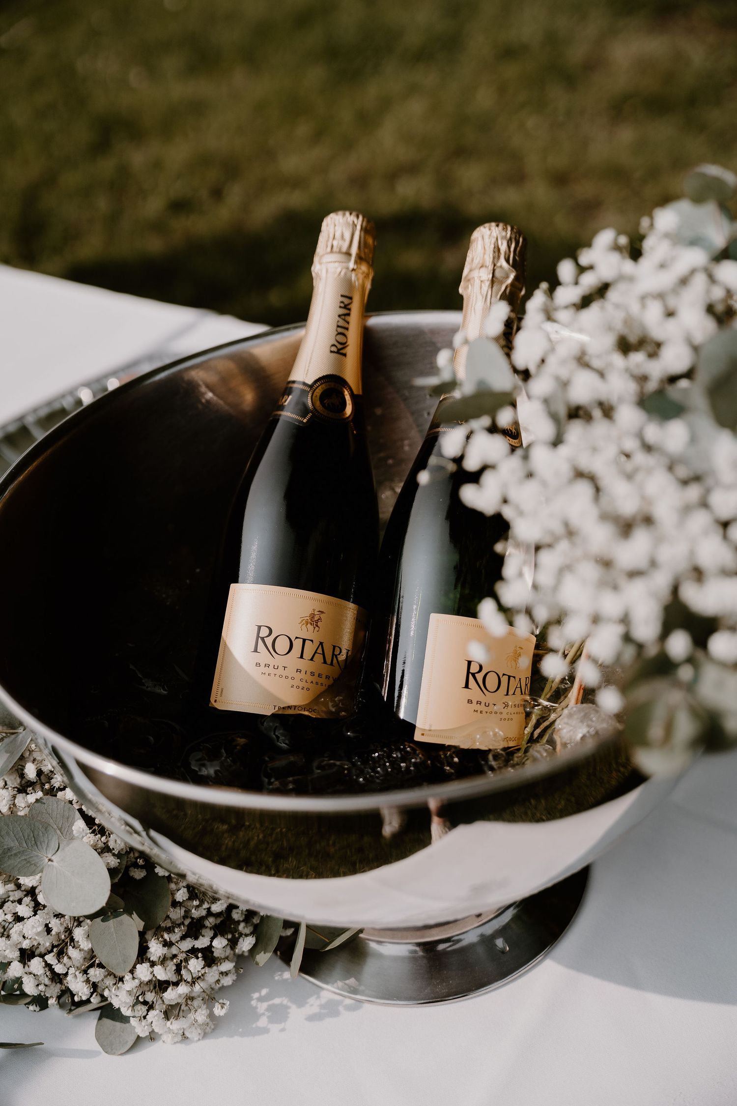Champagne bottles nestled in an elegant ice bucket with delicate white flowers for a luxurious celebration.