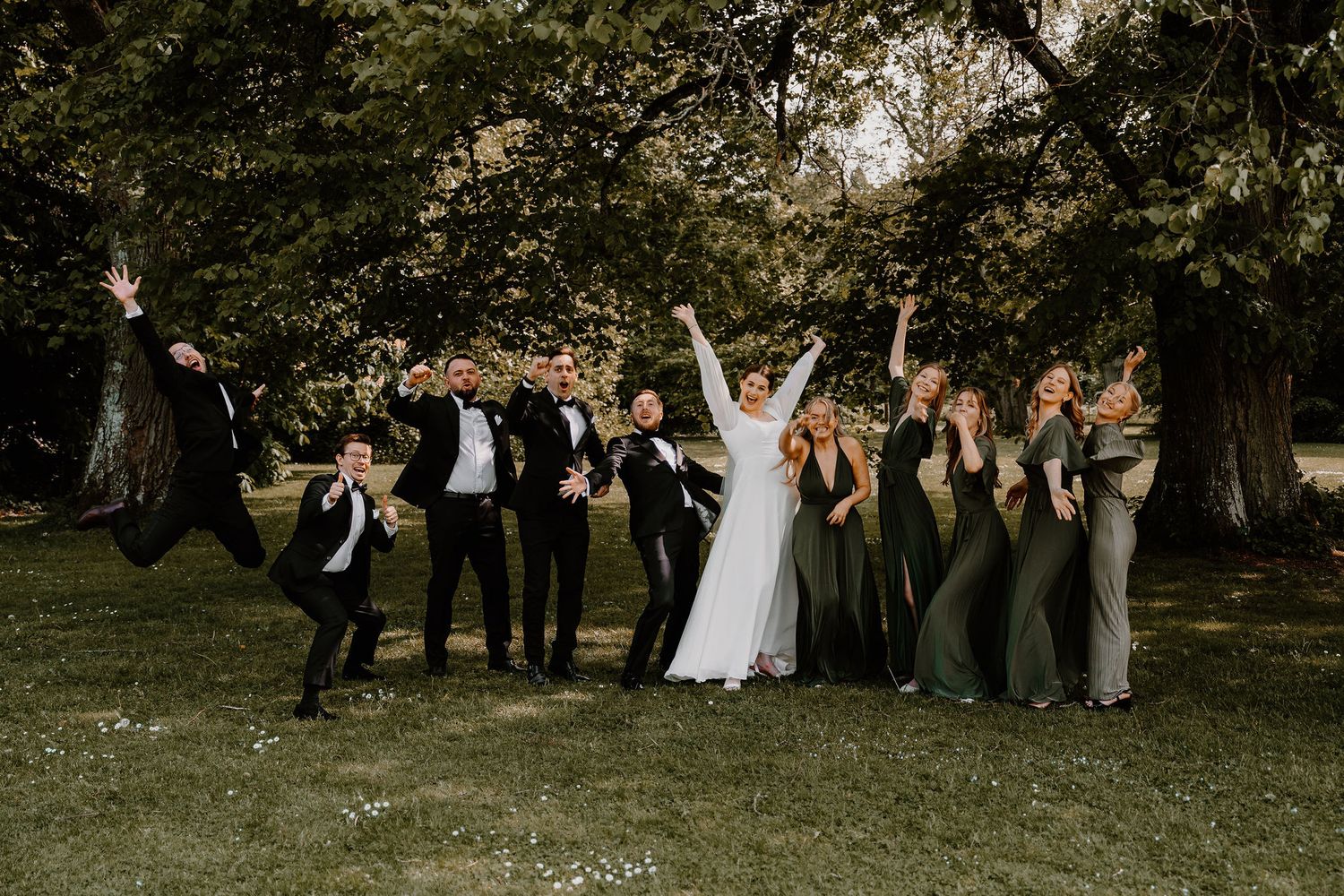 Wedding party celebrates joyfully in a sunlit orchard during a spring outdoor ceremony.