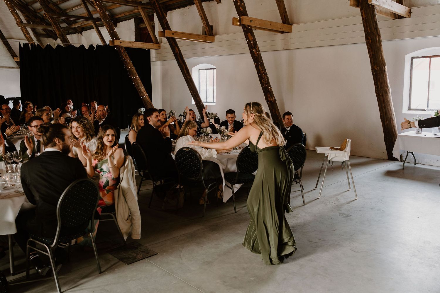 A celebration dining event takes place in a rustic attic space with exposed wooden beams and white walls.