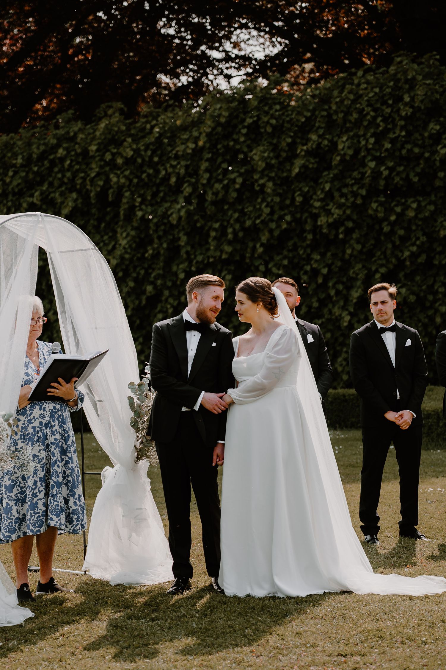 Five photos show a wedding party in a garden setting with flowing gowns and natural outdoor lighting.