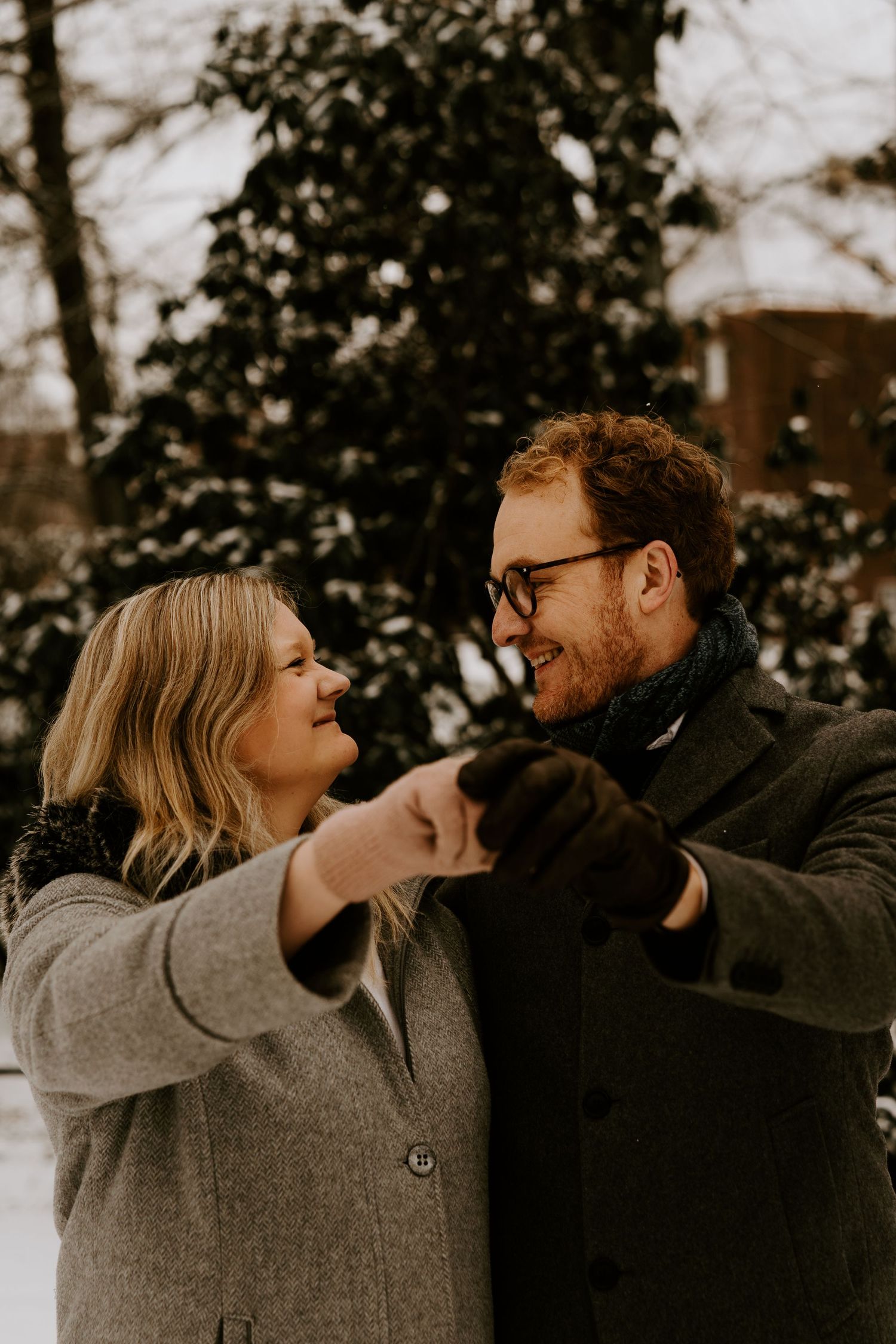 Two people in winter coats share a joyful moment together outside in a moody winter setting.