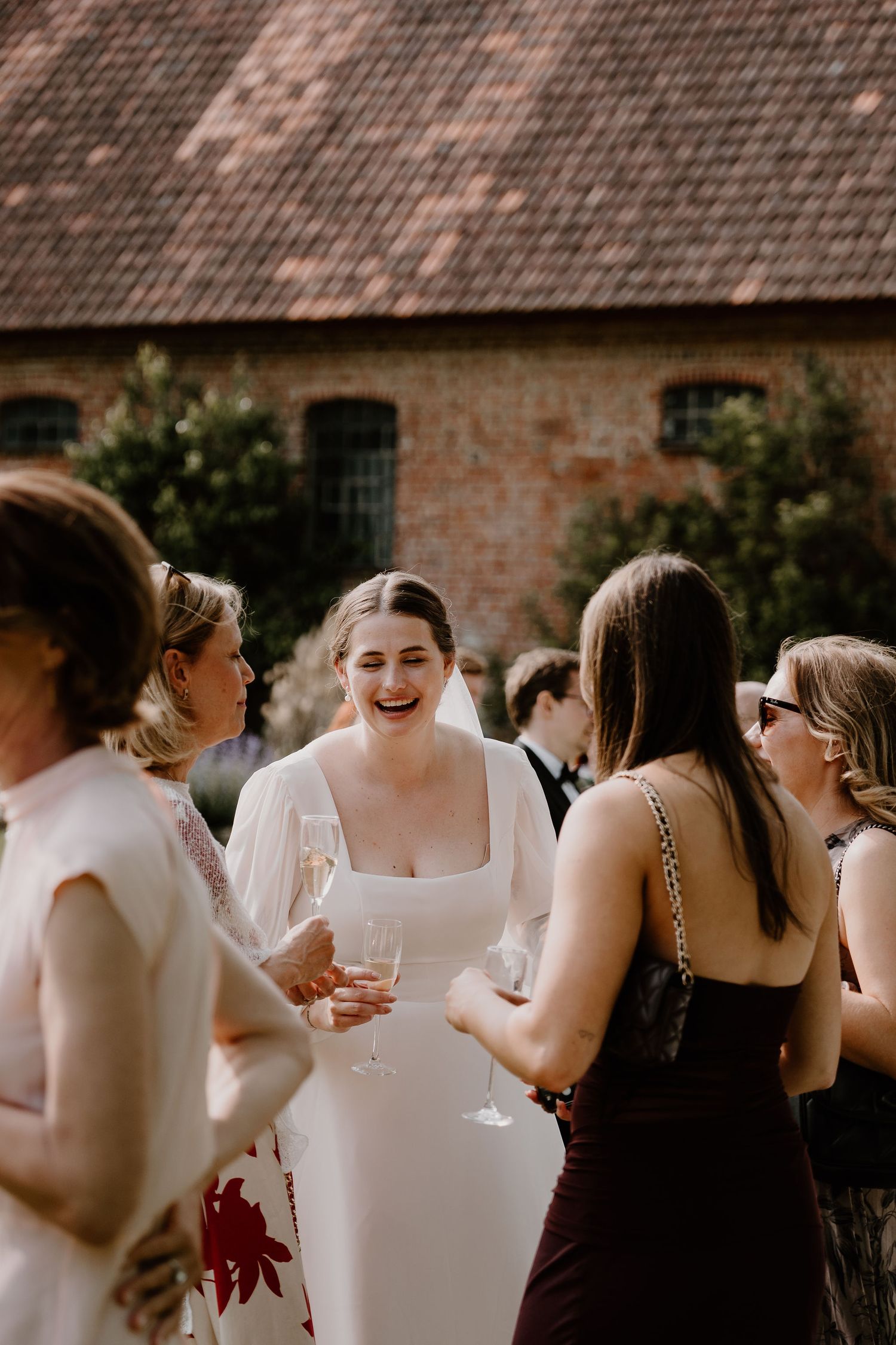Wedding guests gathered outdoors for cocktail hour at rustic stone venue with drinks and conversation.
